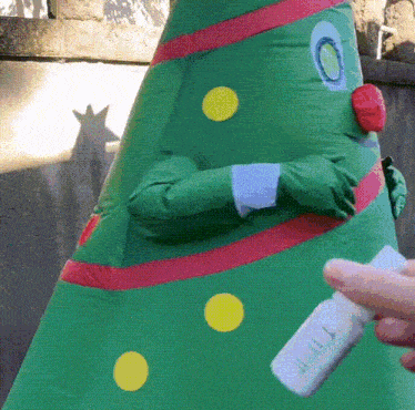 a green inflatable christmas tree is being held by a person
