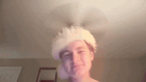a man wearing a santa hat is standing in front of a fan