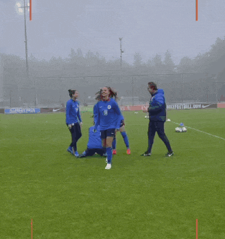 a group of soccer players are on a field with a nike football.com sign in the background
