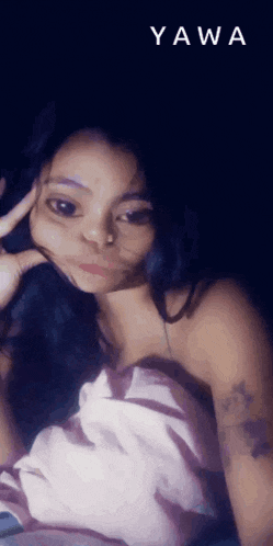 a woman with a tattoo on her arm is laying on a bed with the word yaw written on the bottom right