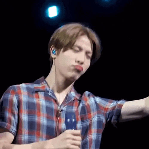 a man in a plaid shirt is making a funny face while wearing ear buds .