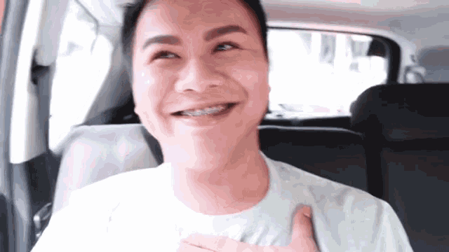 a man is sitting in the back seat of a car smiling .