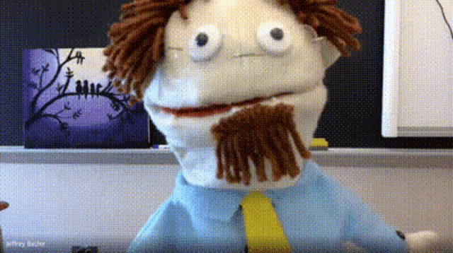 a puppet with glasses and a beard is standing in front of a blackboard