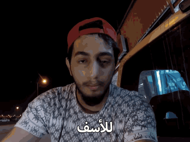 a man wearing a red hat and a t-shirt with arabic writing on it
