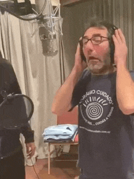 a man wearing headphones is singing into a microphone in a studio .