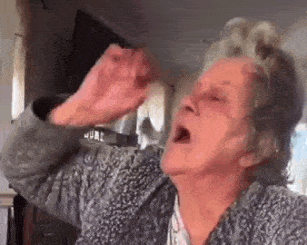 an elderly woman is making a funny face with her mouth open while sitting in a living room .