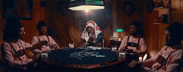 a group of men are sitting around a poker table playing cards