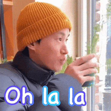 a man wearing a yellow beanie is drinking from a cup and the words oh la la are above him