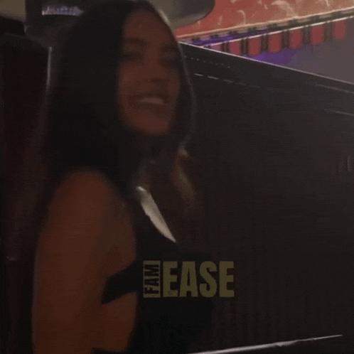 a woman in a black dress is smiling in front of a sign that says ease