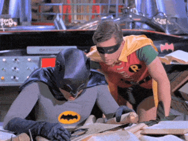 batman and robin look at a piece of paper in front of a batmobile