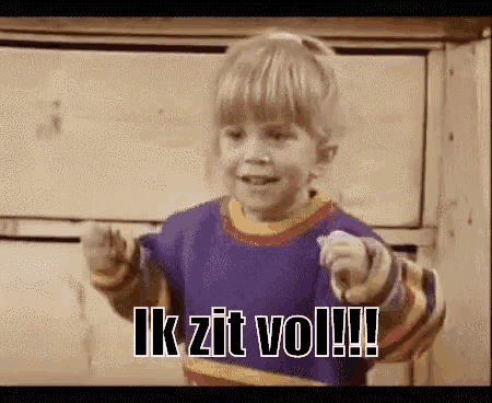 a little boy is pointing at the camera with the words ik zit vol written on it .