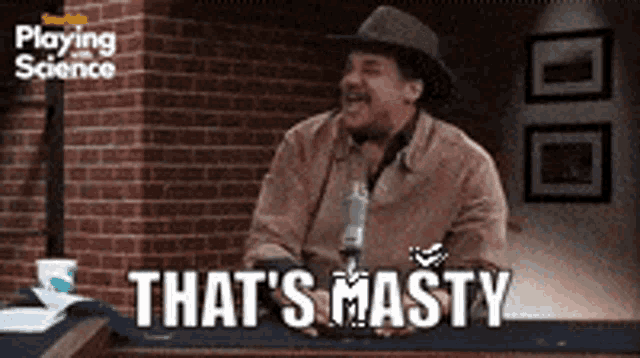 a man in a cowboy hat says that 's masty in front of a microphone .