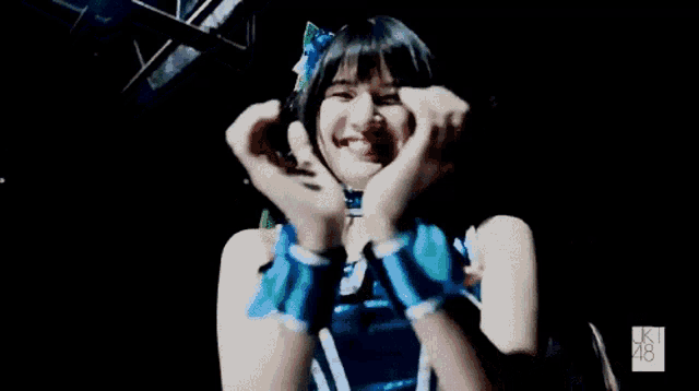 a young girl is making a heart shape with her hands .