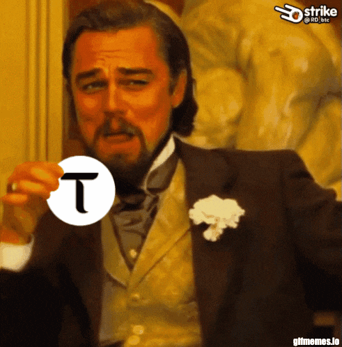a man in a suit holds a white circle with a letter t on it