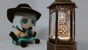 a stuffed doll is sitting next to a snow globe with a christmas tree inside