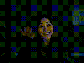 a woman is smiling in a dark room with a black background