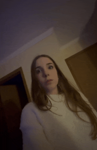 a woman with long hair is standing in a hallway