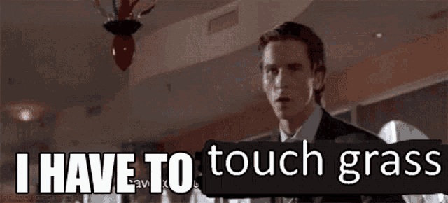 a man in a suit and tie is standing in a room with the words `` i have to touch grass '' .