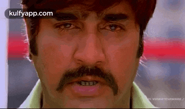 a close up of a man 's face with a mustache making a funny face .