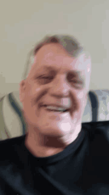a man in a black shirt is smiling and looking at the camera