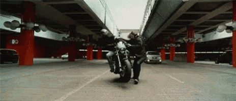a man is doing a trick on a motorcycle in a parking lot .