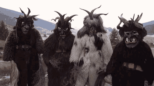 four people dressed in furry costumes with horns stand in front of a mountain