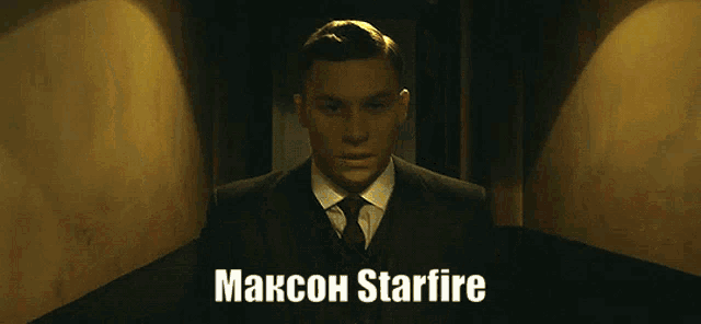a man in a suit and tie is standing in a dark hallway with the name maxcon starfire on the bottom