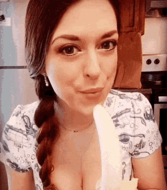 a woman in a braid is eating a banana in a kitchen