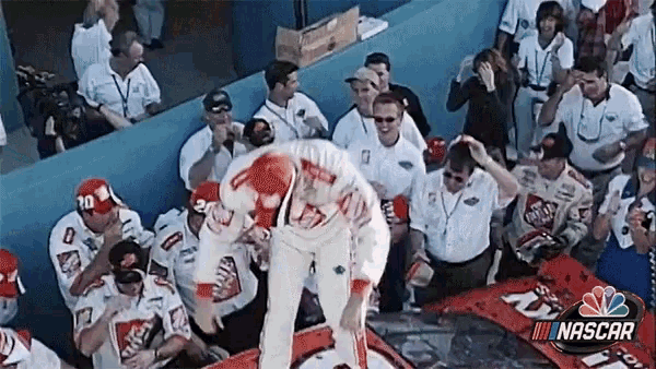 a group of people are watching a nascar race and one of the sponsors is home depot