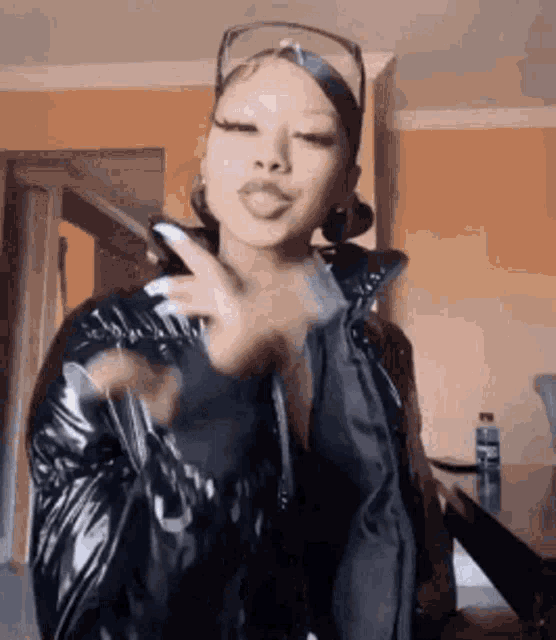 a woman in a black jacket is giving a peace sign .