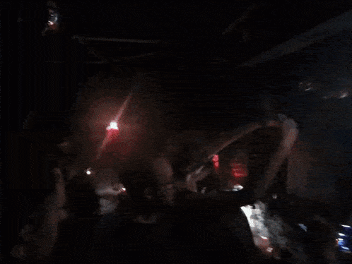 a crowd of people are dancing in a dark room with a disco ball in the background