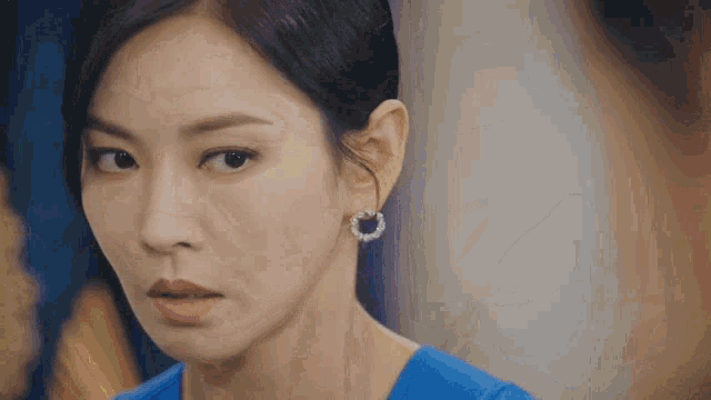 a woman in a blue shirt is holding a blue and white cup of tea