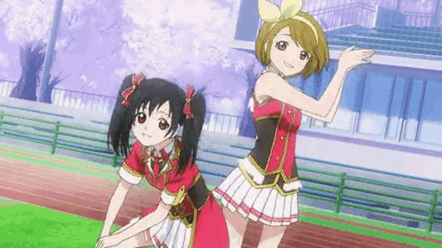 two anime girls are dancing together on a track .