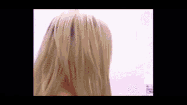 a close up of a woman 's blonde hair against a white wall
