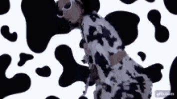 a woman in a cow print dress is dancing in front of a cow print .