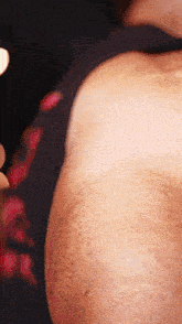 a close up of a person 's arm with a black shirt with red flowers on it