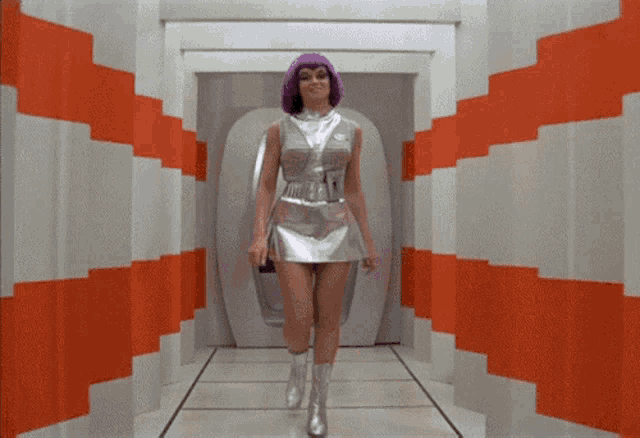 a woman in a silver dress and purple hair is walking through a hallway