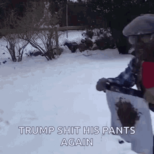 a man is standing in the snow holding a bag of snow and says `` trump shit his pants again '' .