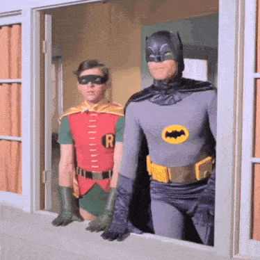 batman and robin are looking out a window together