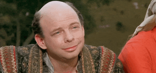a man with a bald head and a red shirt is smiling for the camera