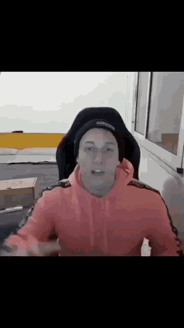 a man in a pink hoodie is sitting in a chair .