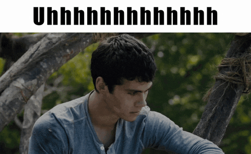 a man in a blue shirt sits in front of a tree with the words uhh on the top