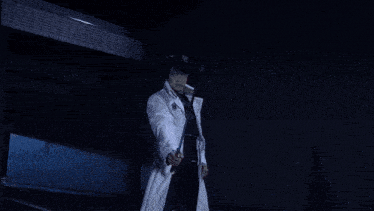 a man in a white coat is standing in front of a light coming from above