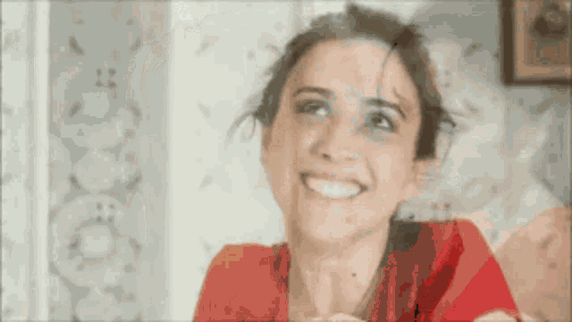 a woman in a red shirt is smiling and looking up at the camera