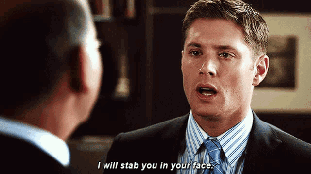 a man in a suit and tie is talking to another man and says i will stab you in your face