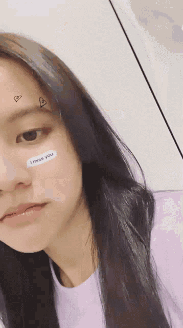 a girl with a sticker on her face that says " i miss you "
