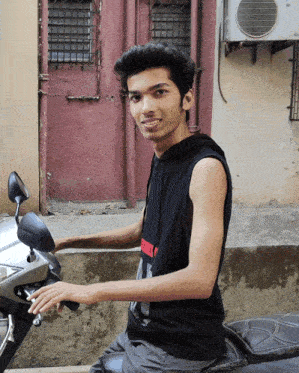 a young man is sitting on a motorcycle wearing a black tank top that says ' freedom ' on it