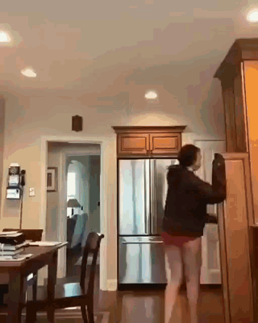 a woman in shorts is standing in a kitchen next to a fridge .