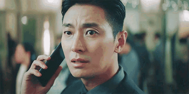 a man is talking on a cell phone with a serious look on his face