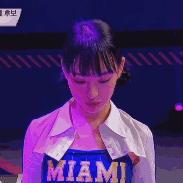 a woman wearing a miami shirt looks down